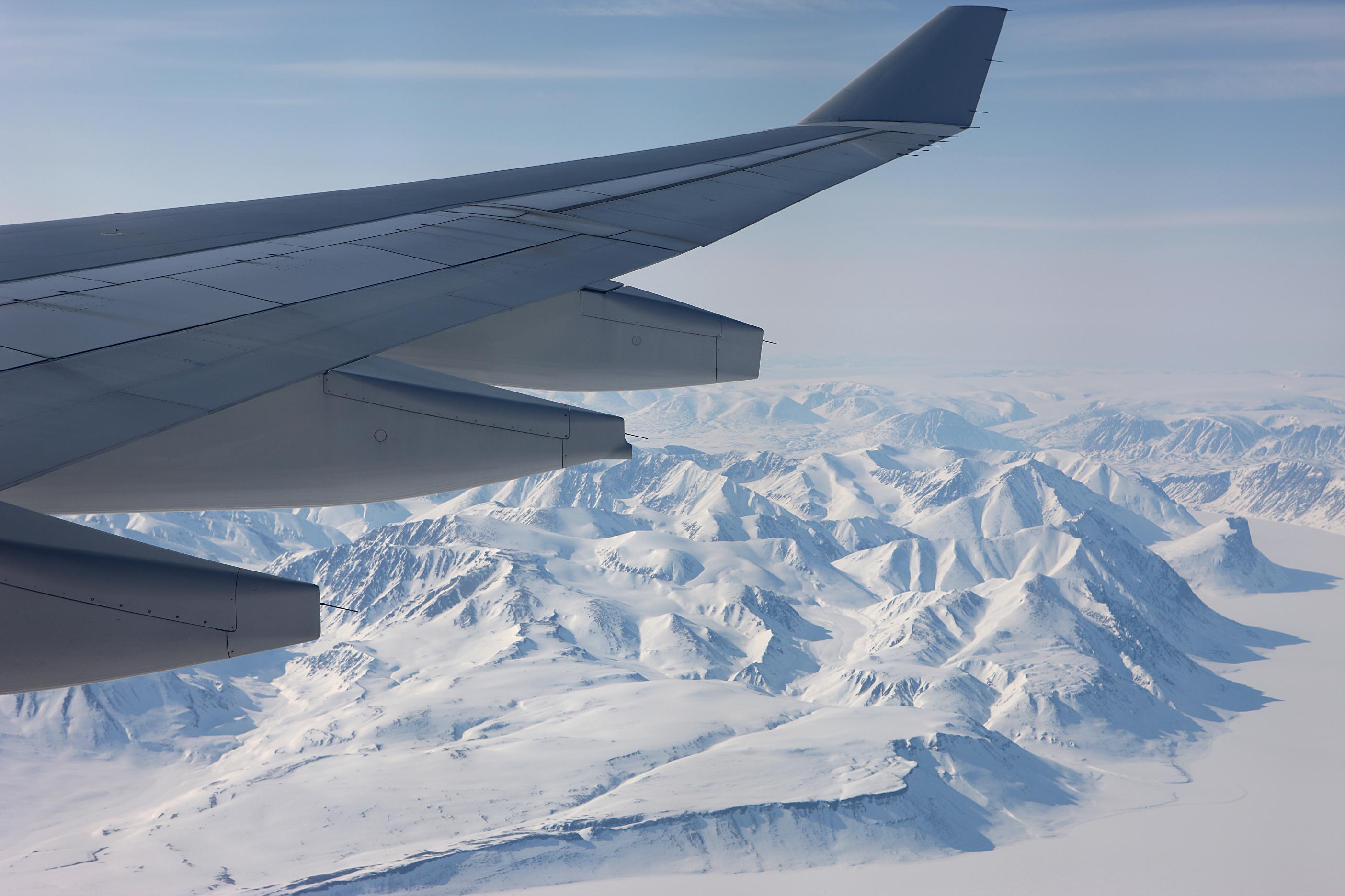 Ein Flugzeugflügel und im Hintergrund die Schneelandschaft von Spitzbergen.